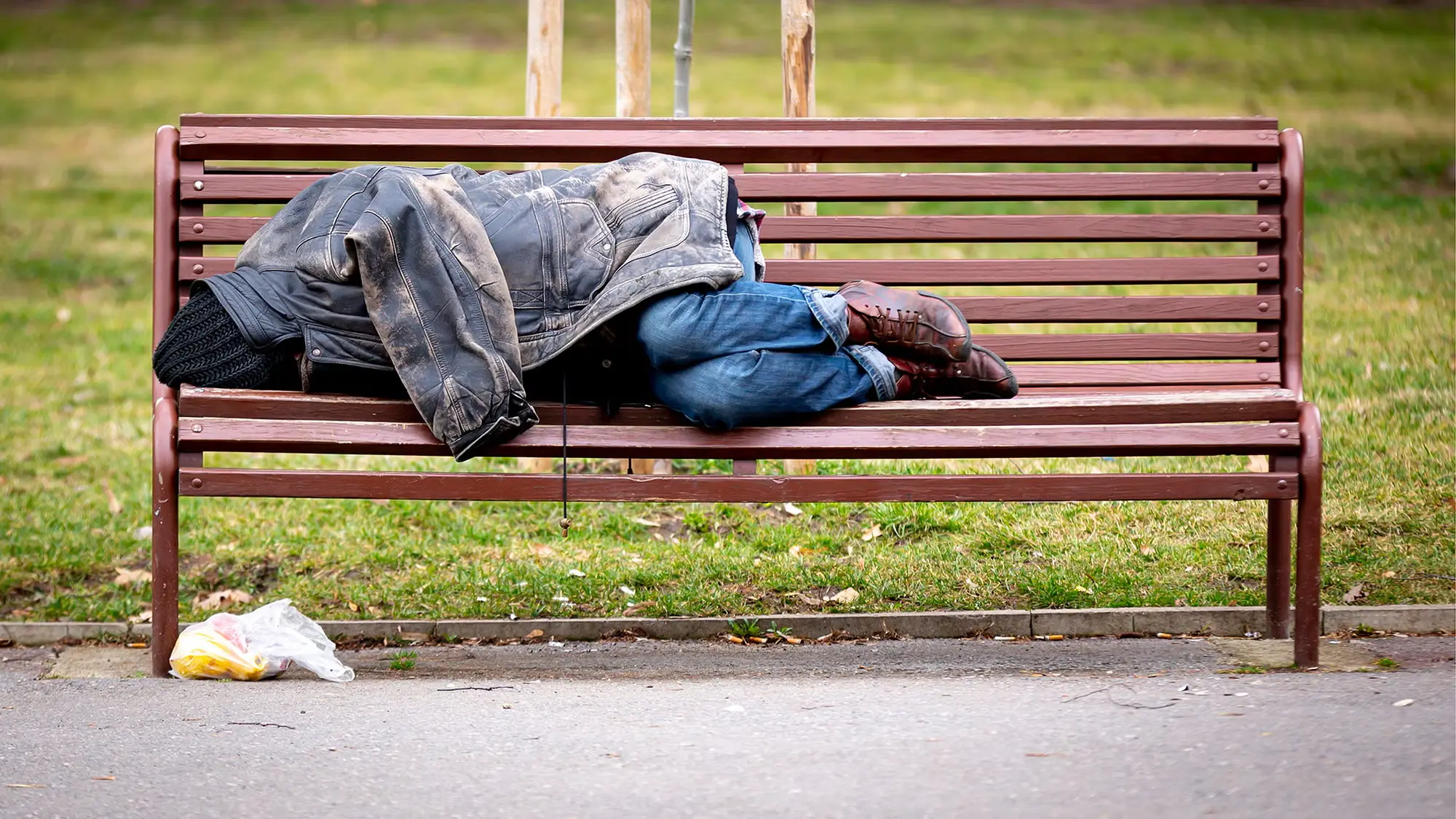 Homeless man asleep on a bench