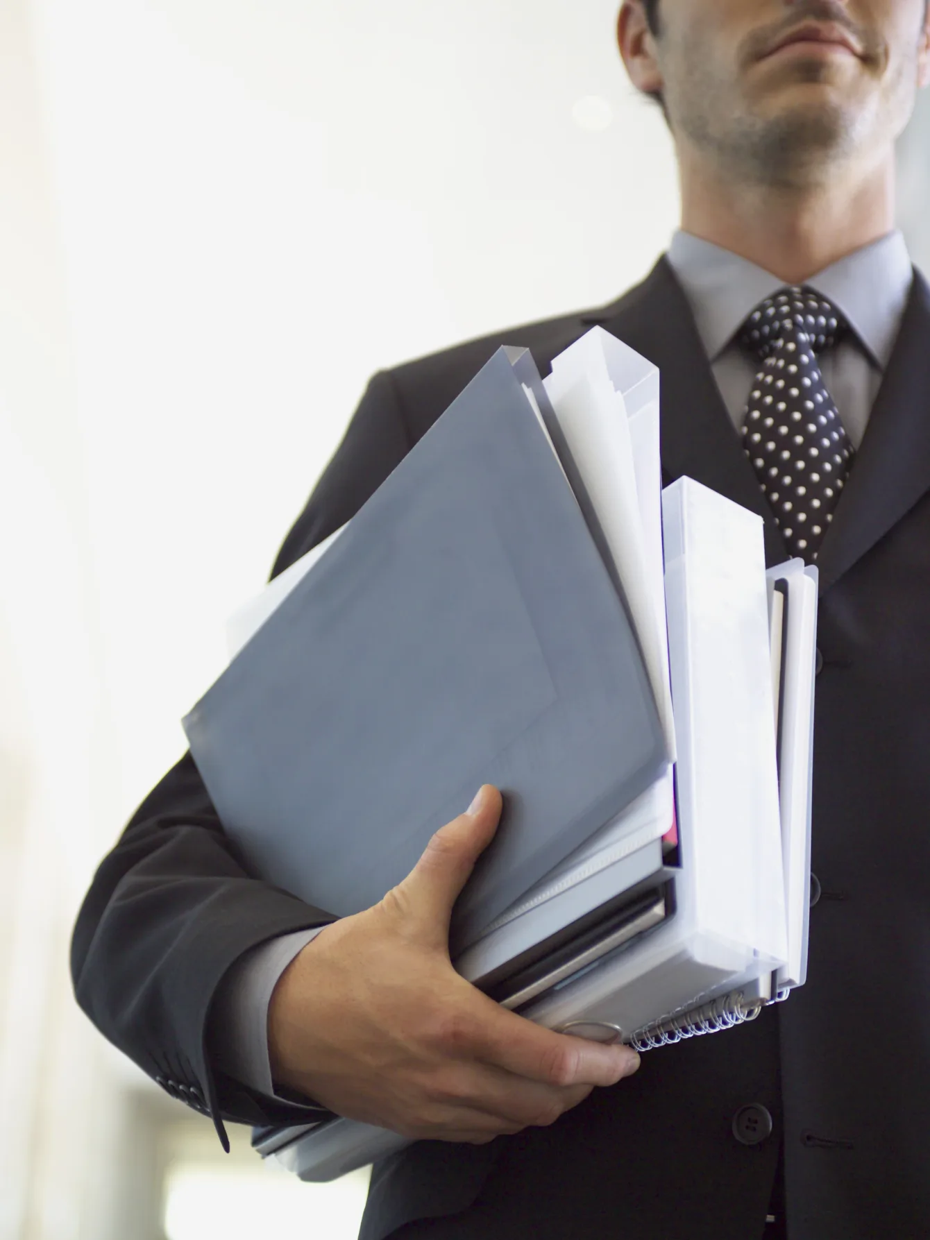 Man dressed in a suit and carrying bags and files from the 2014 election race under his arm