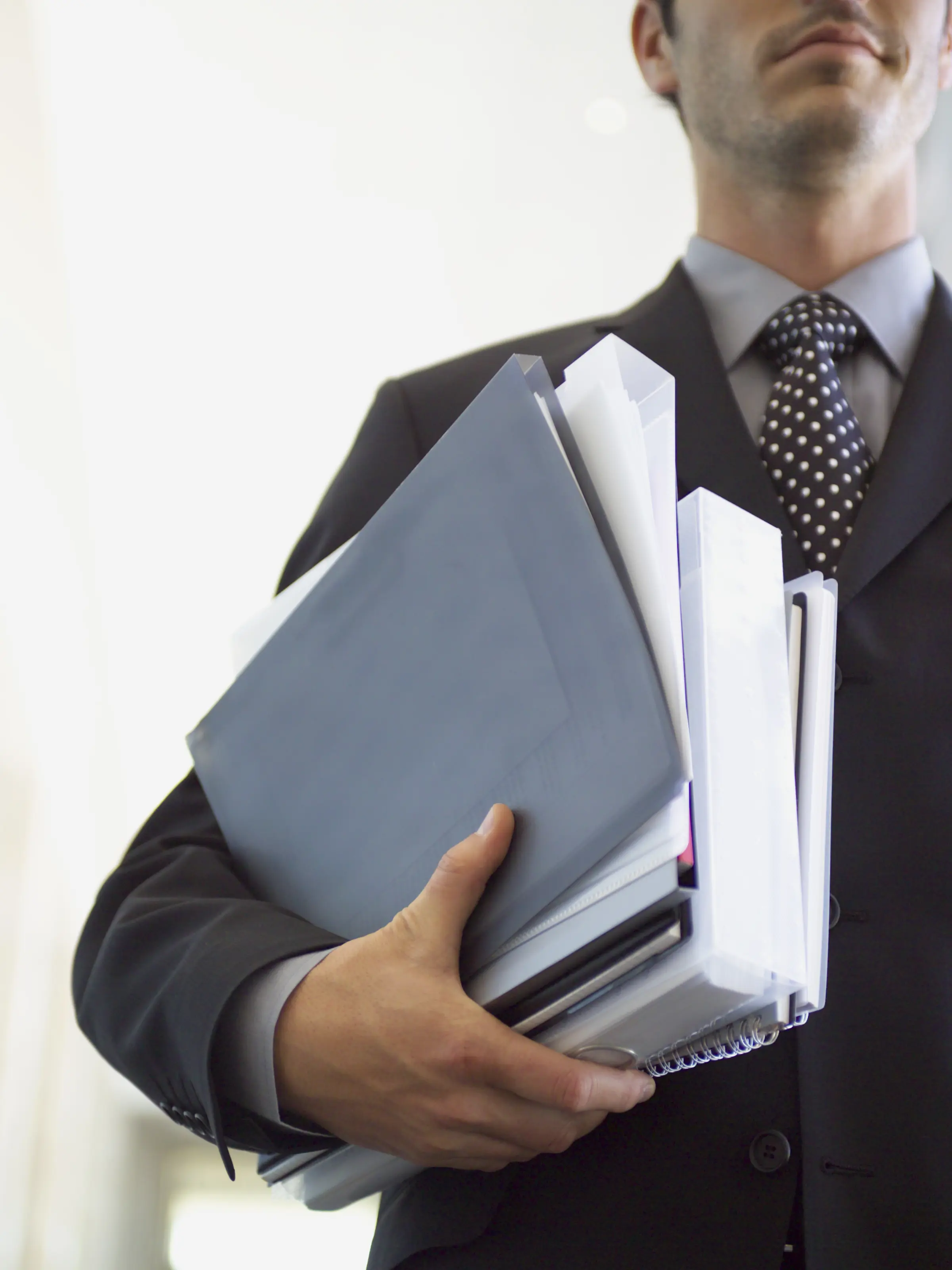 Man dressed in a suit and carrying bags and files from the 2014 election race under his arm